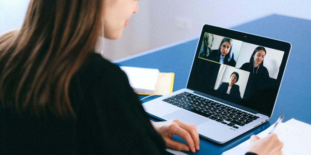 A woman looks at a laptop showing a Zoom meeting