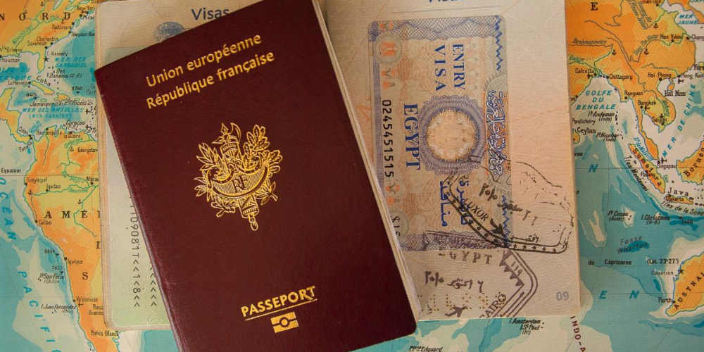 A passport sits on a map-covered table