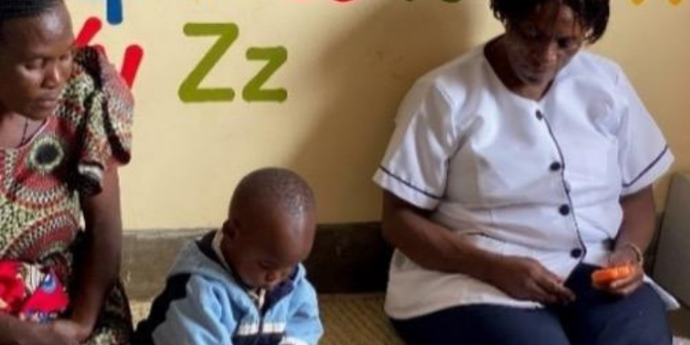 A nurse and mother watch a young boy play on the floor.