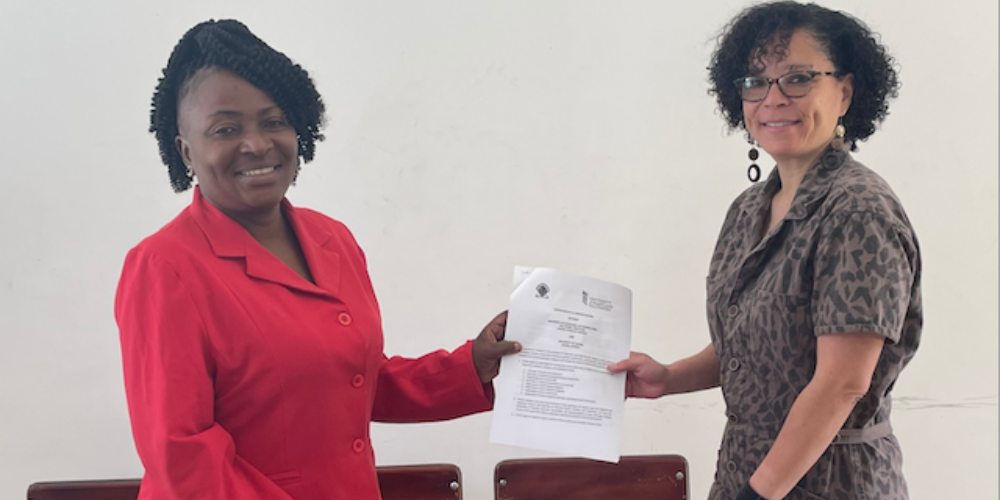Patricia Mwila-Sakala of the University of Zambia and Lynn Michalopoulos of the University of Maryland School of Social Work hold an agreement between them

