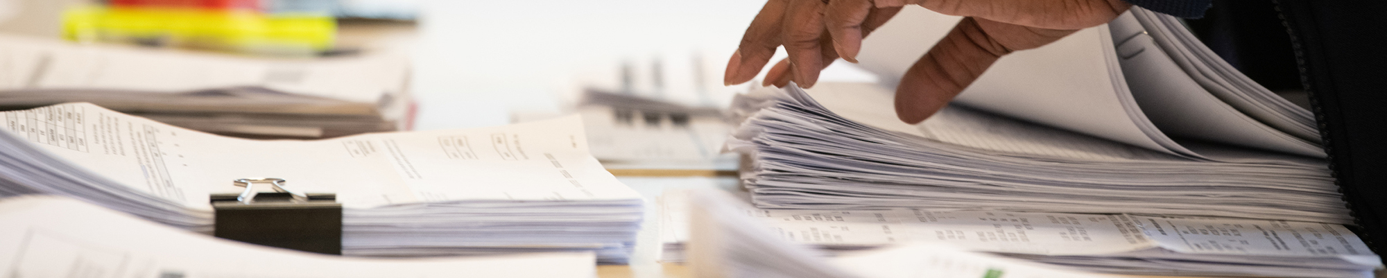 A hand rifles through stacks of financial paperwork