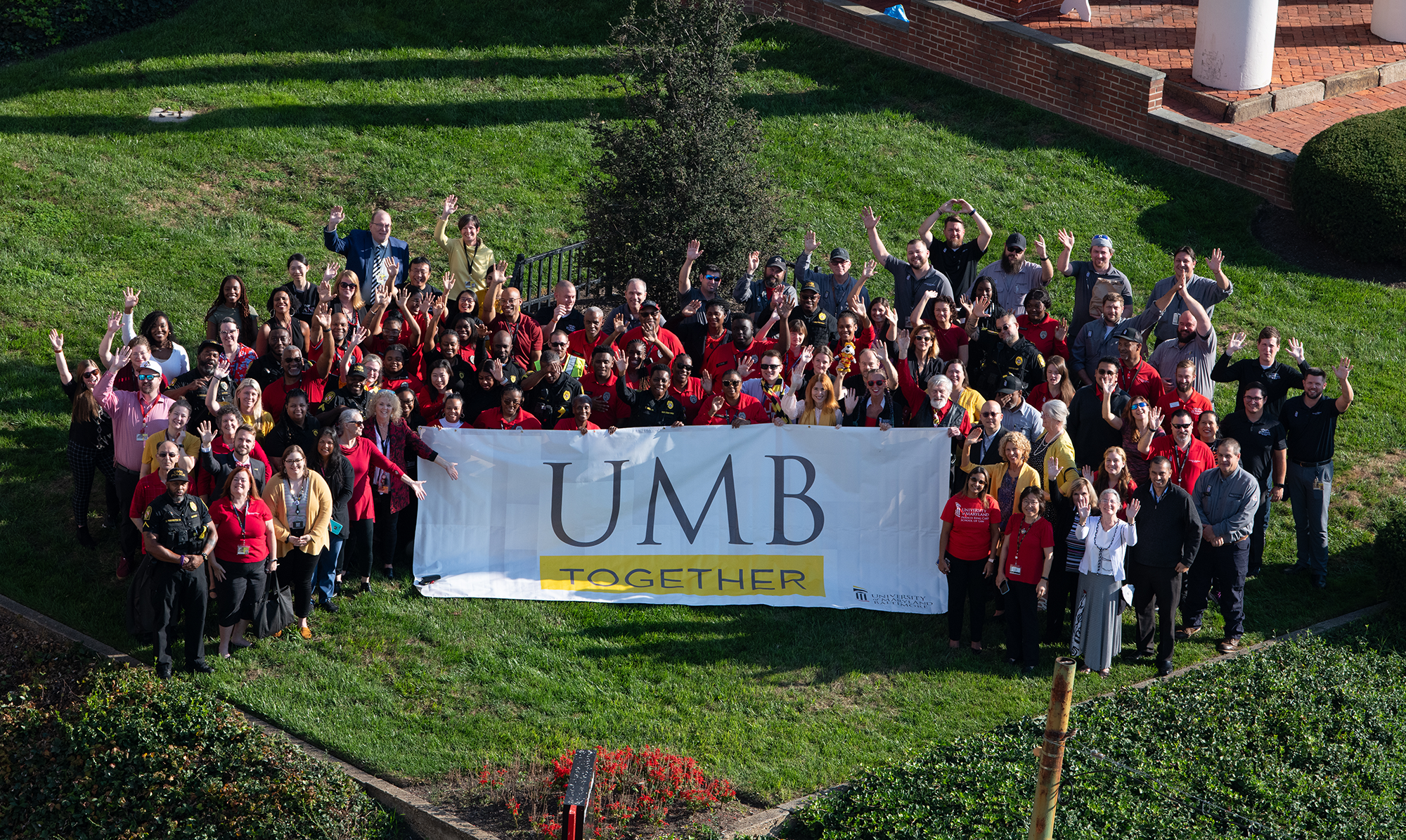 Faculty and Staff Holding a UMB Together Banner