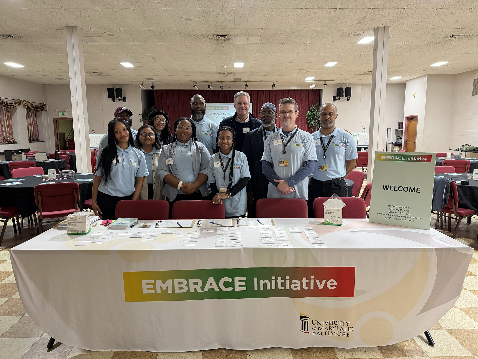 EMBRACE staff members posing behind a table with information about their programs and services