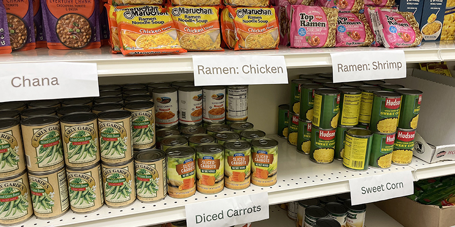 Food supplies on a shelf, including chana, ramen, canned beans, carrots, and potatoes