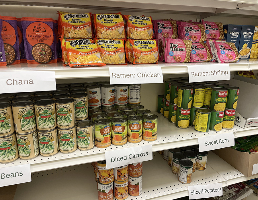 Food supplies on a shelf, including chana, ramen, canned beans, carrots, and potatoes