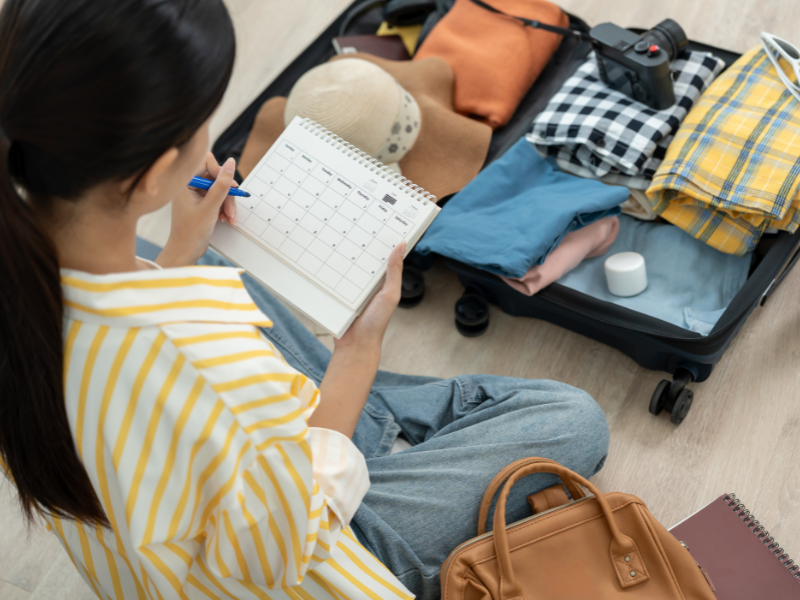 A woman sits on the floor packing a suitcase