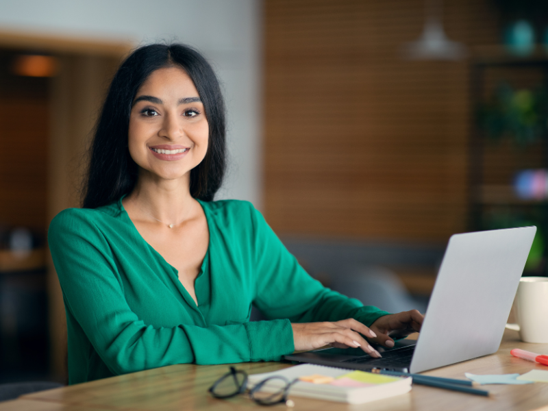 A woman sits at a laptop