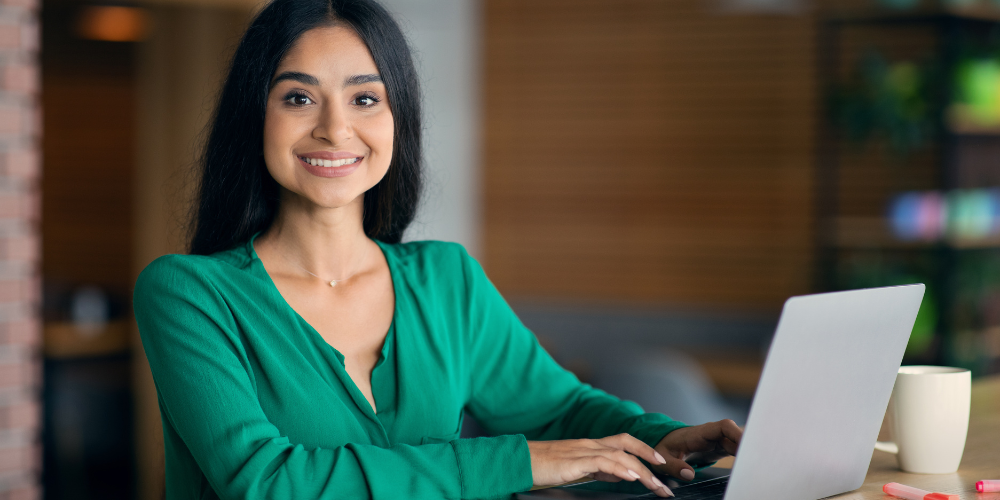 A woman sits at a laptop