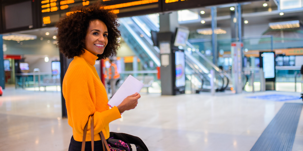 A woman stands with a suitcase in a train station