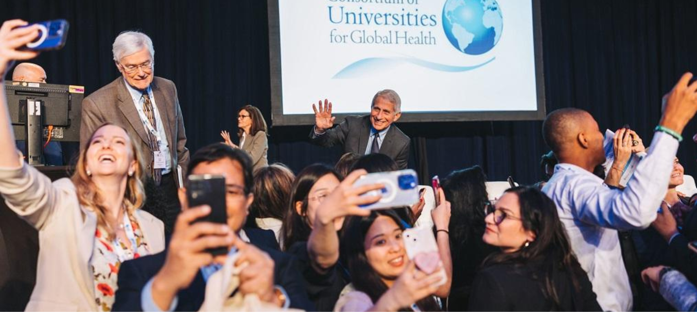 People taking selfies of Dr. Anthony Fauci, who's onstage at the CUGH 2023 conference