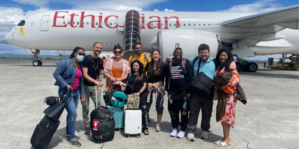 A group from UMB stands on a runway beside an Ethiopian Airlines plane.