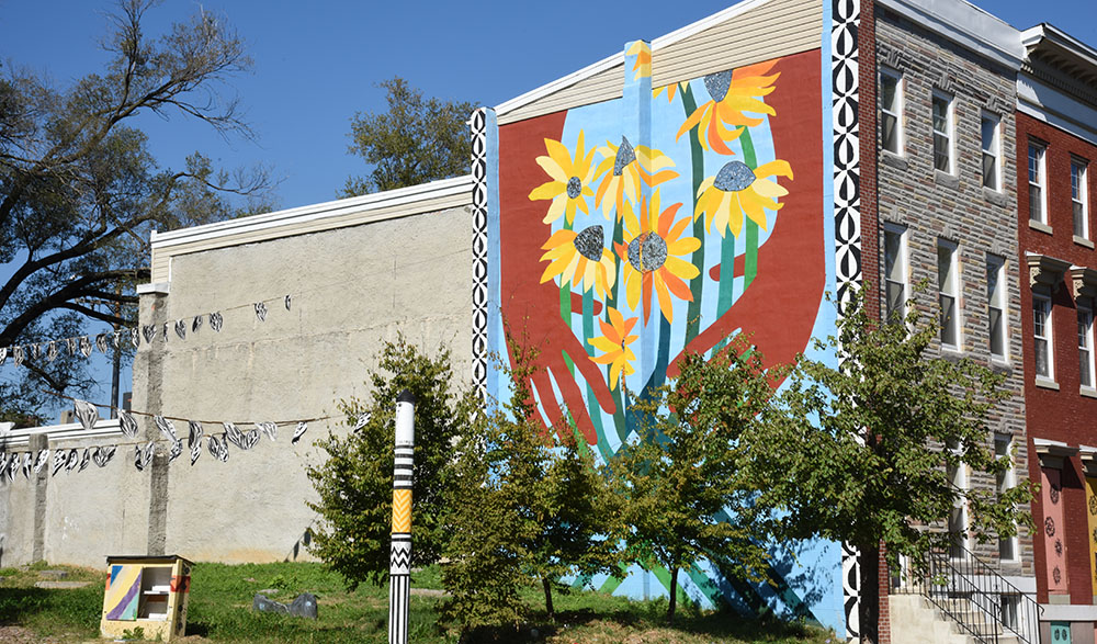 Colorful sunflower mural with hands in Baltimore's Franklin Square Neighborhood