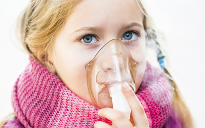 A child uses a nebulizer to treat her asthma.