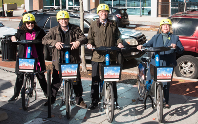Linda Cassard, MBA; Jon M. Laria, JD ’92; James L. Hughes, MBA; and Jane M. Shaab pose with bikes near the station at the UM BioPark.