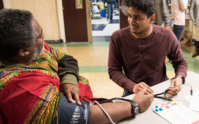 School of Medicine student Nabid Ahmed screens the blood pressure of Project Feast guest Anthony Clark on Nov. 23, 2017.
