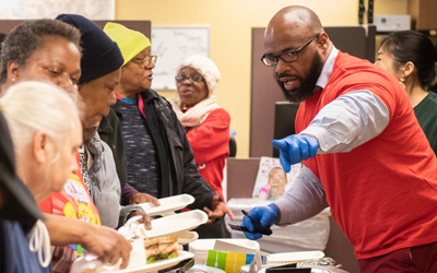 Tyrone Roper, MSW, the new director of the UMB Community Engagement Center, serves lunch to West Baltimore neighbors at the monthly community lunch.