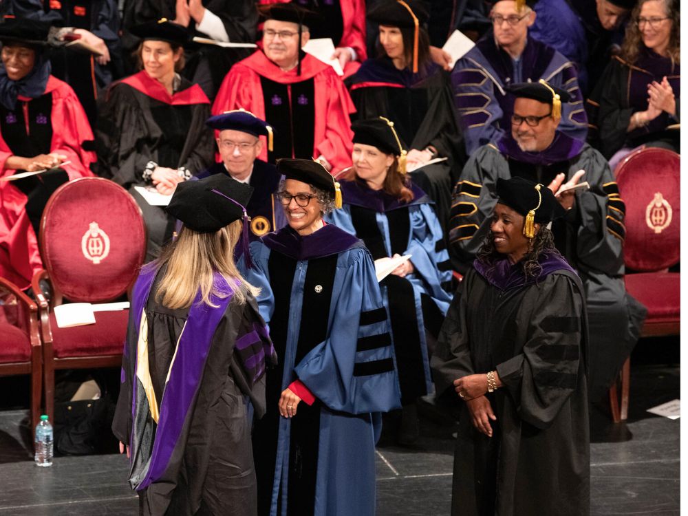 Dean Renée Hutchins Laurent congratulates a graduate as keynote speaker Sherrilyn Ifill looks on.