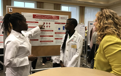 Shereen Farquharson (left) and Emani Clifton-Malone (middle) present their research poster on Gestational Trophoblastic Disease Prevalence Among African Americans.