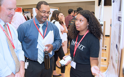 Bret Hassel, PhD, Associate Professor at SOM and Director of Nathan Schnaper Intern Program in Translational Cancer Research (left), and Gregory B. Carey, PhD., Associate Professor and Director of Student Research and Community Outreach at UMSOM (center), listen to poster presentations from the students.