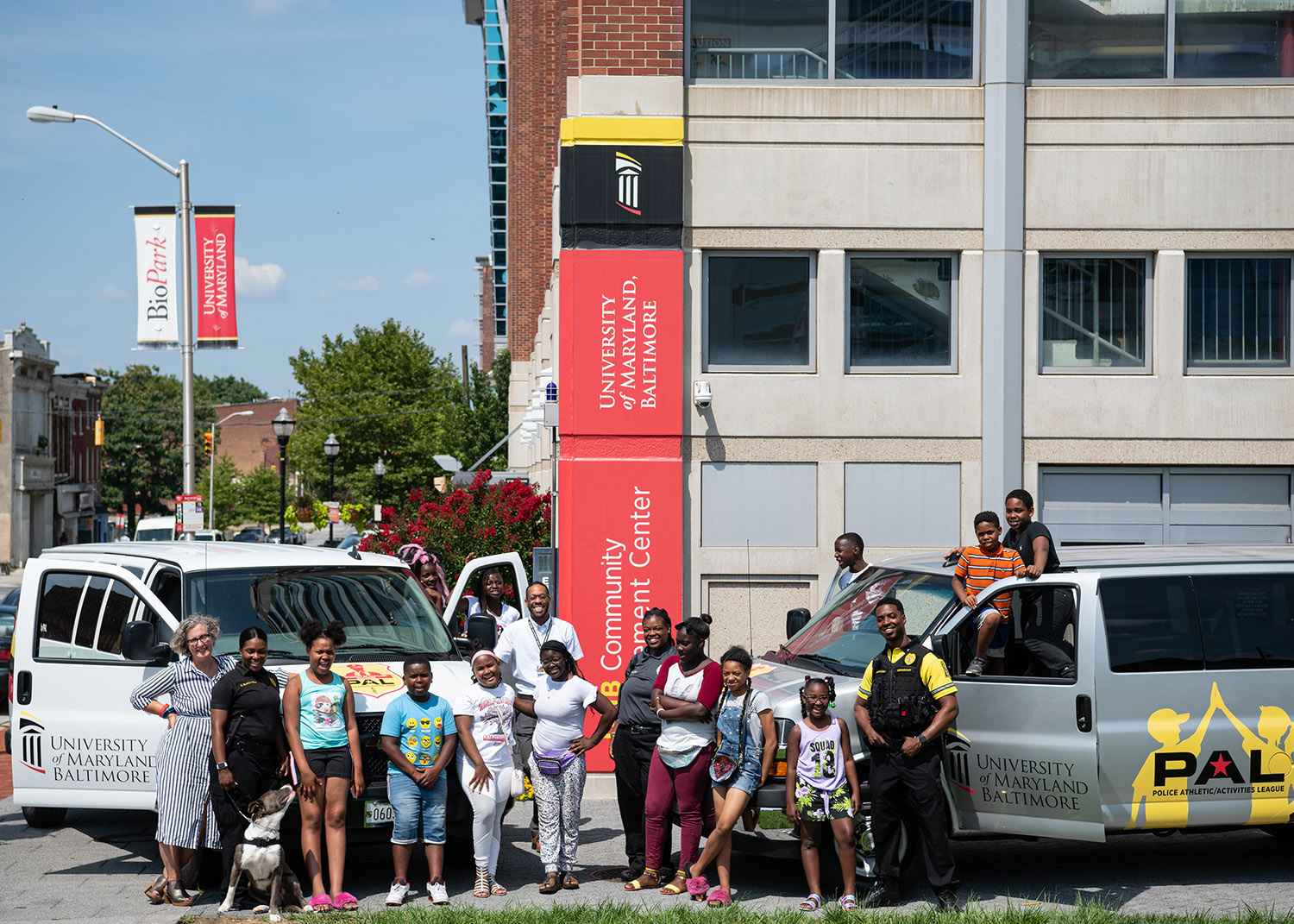 a group of adults and children gather for a photo in front of public safety vehicles