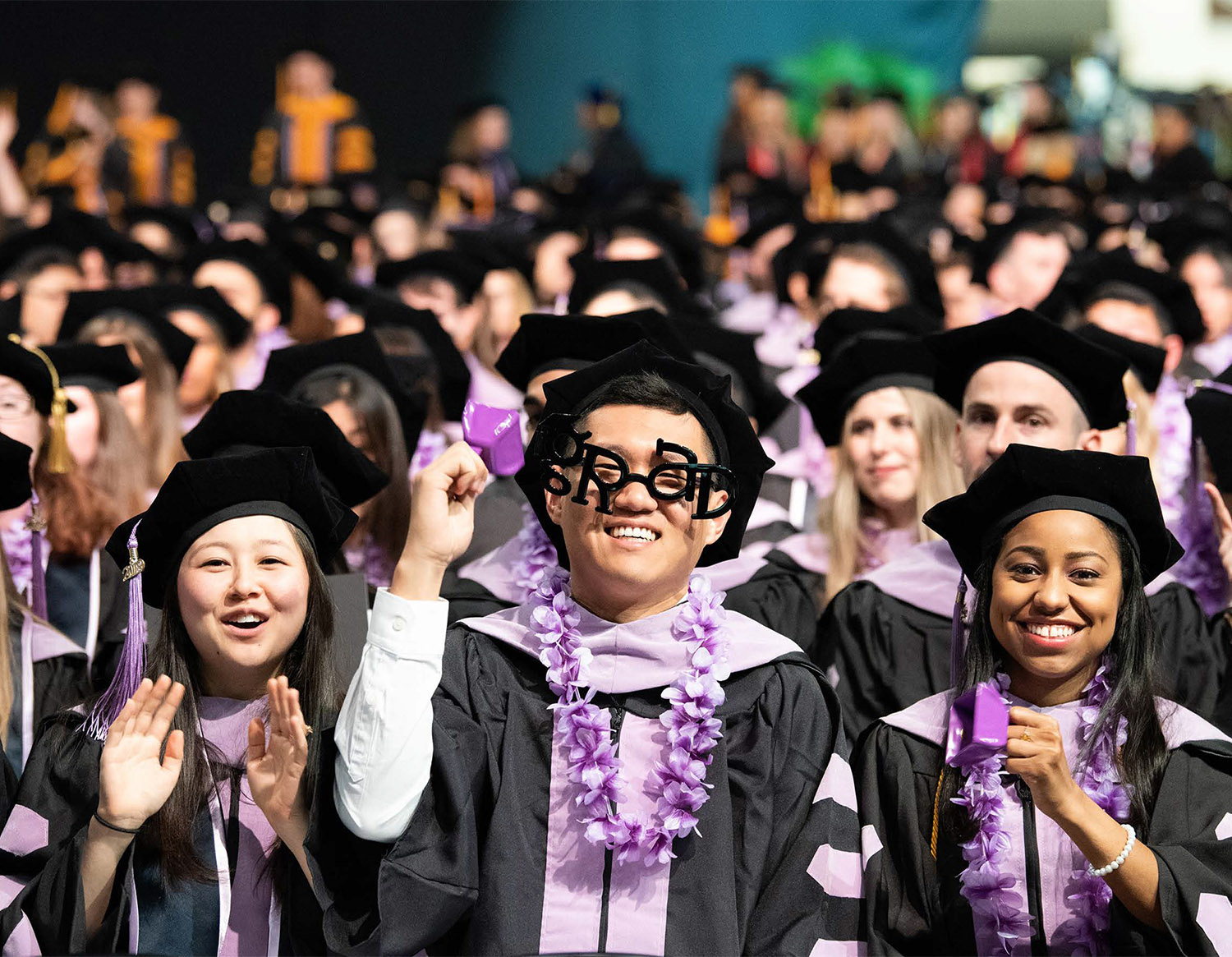 Students at Commencement celebrate in full regalia, one student wears 