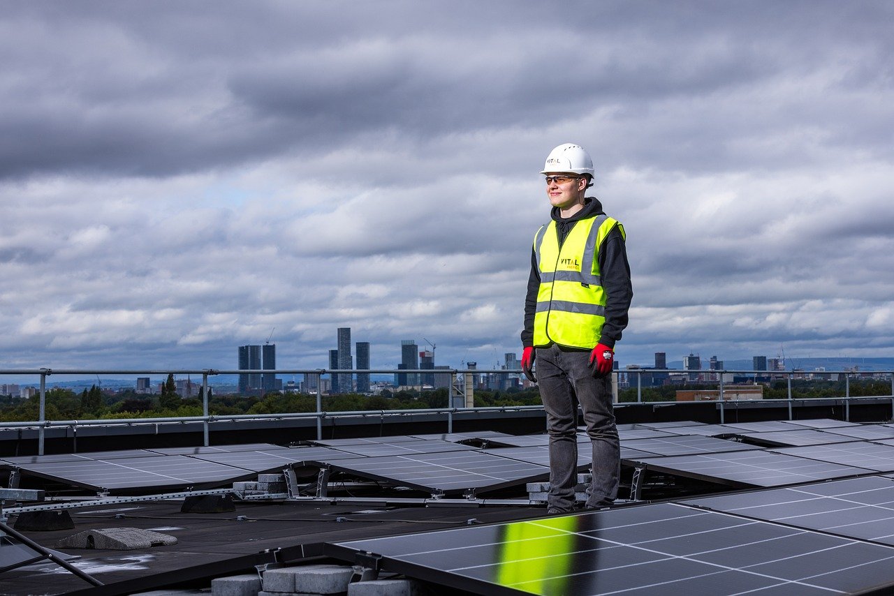 construction worker standing by solar installation on rooftop